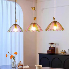 Three scalloped colored glass pendant lights with butterfly accents illuminating a dining area.