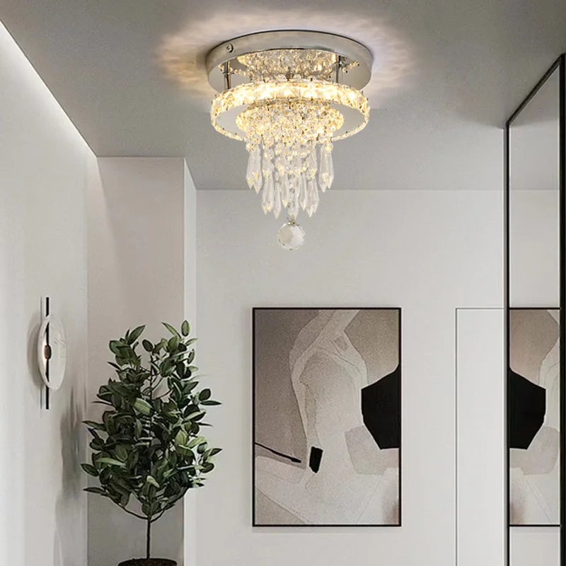 A chrome and crystal tiered ring flush mount ceiling light installed in a modern interior with abstract art and a plant.