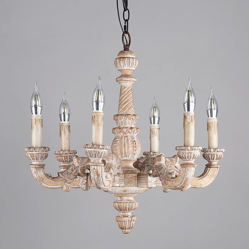 Slightly angled front view of a distressed wood candelabra chandelier showcasing its carved details and candle-shaped light sockets.