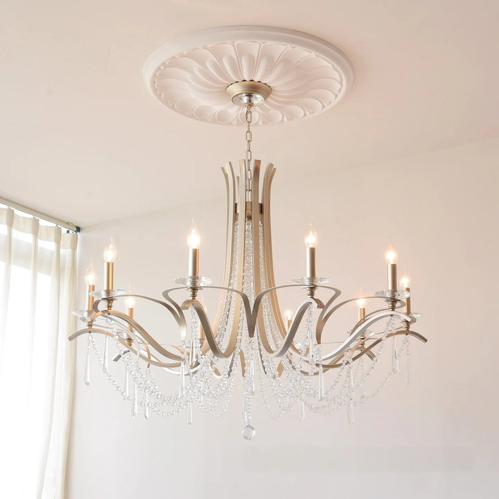 A spacious room featuring a brushed gold tiered crystal chandelier as the central light fixture.