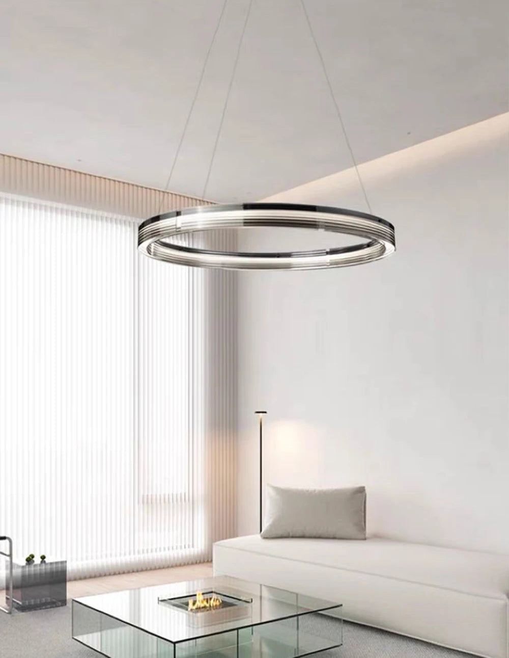 Modern chandelier in a living room setting with a white sofa and glass coffee table.