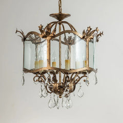 Front view of a gold crystal chandelier with multiple light sources and ornate detailing.