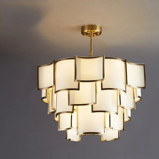 A multi-tiered pendant light with square frosted glass shades and a gold frame, illuminated against a gray ceiling.