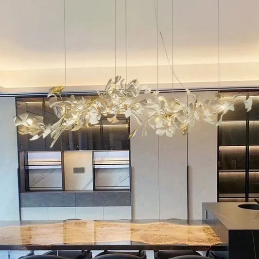 Gold ginkgo leaf chandelier with ceramic leaves, hanging in a modern dining room