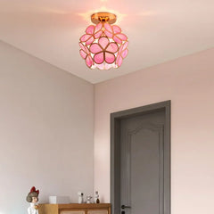 A pink flush mount ceiling light with acrylic petals in a room with a grey door.
