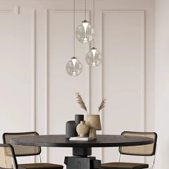 Three clear glass globe pendant lights with metallic accents hanging in a row against a wall with decorative molding.