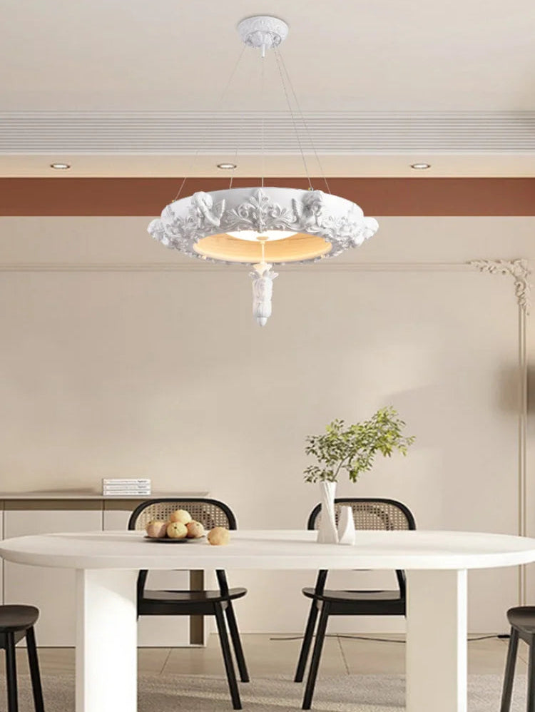 Modern dining room with a stylish chandelier, white table, and black chairs.