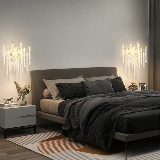 Two gold crystal branch wall sconces flanking a bed in a bedroom setting, providing ambient lighting.