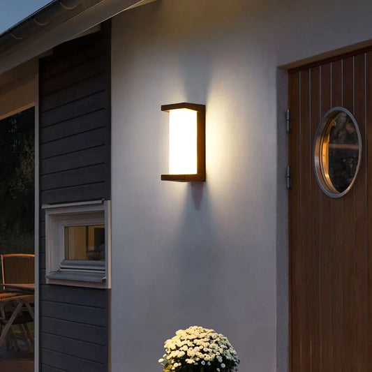 Black rectangular outdoor wall sconce mounted on a white wall with light illuminating upwards and downwards.