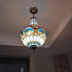 A bedroom scene featuring a Tiffany-style stained glass chandelier with a polished chrome finish, illuminating the room.