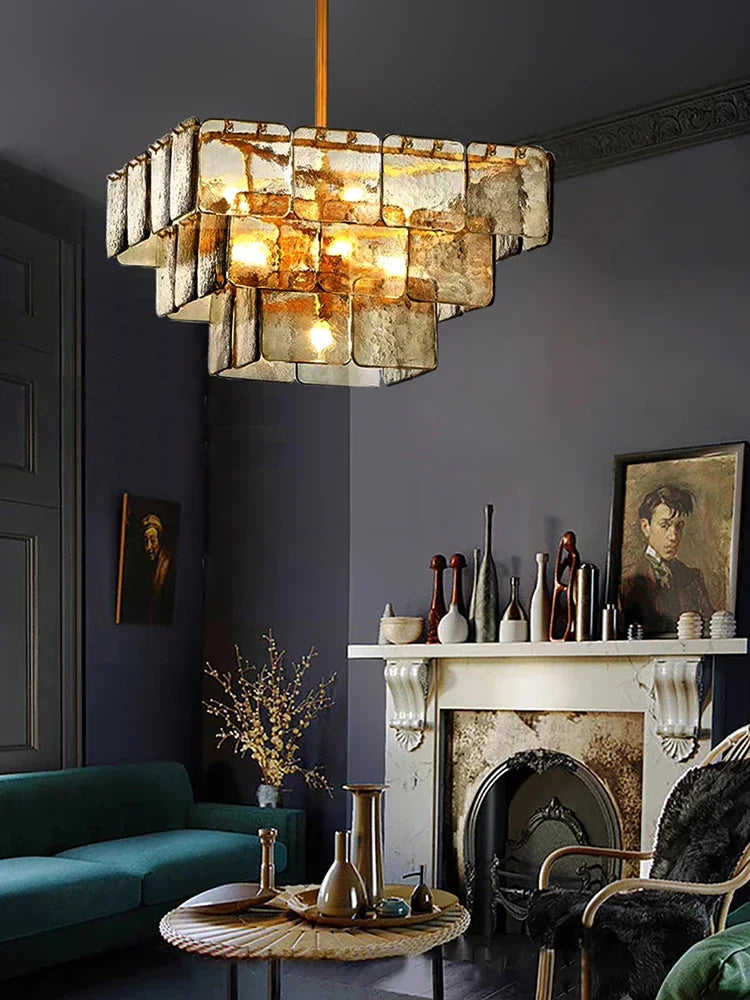A dimly lit, luxurious room with a multi-tiered glass and gold chandelier as the central light source.