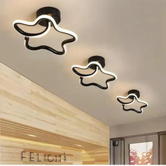 Three black star-shaped semi-flush mount ceiling lights mounted on a light wood paneled ceiling