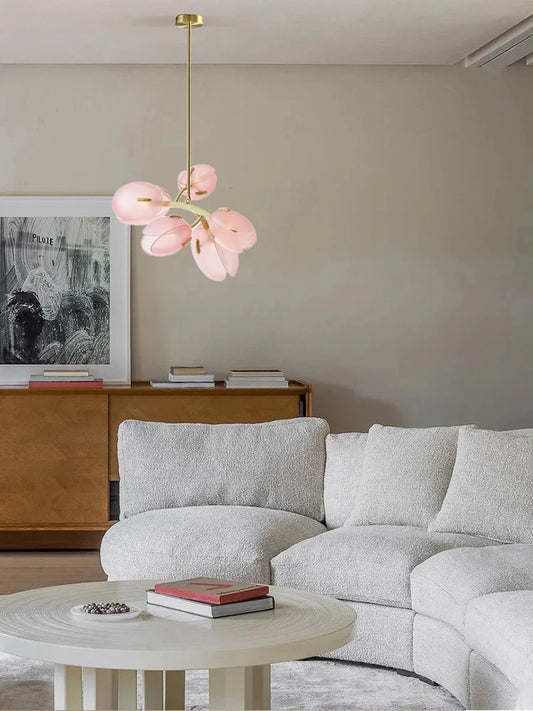 Close-up of a pink floral bud cluster pendant light with a brass finish hanging in a modern living room.
