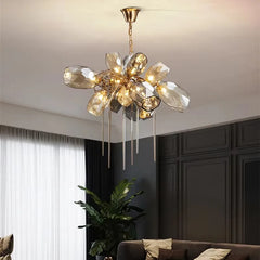 A gold chandelier with faceted crystals is shown hanging above a dining table in a well-lit room.