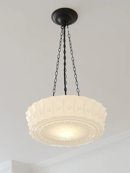 Close-up view of a cream decorative glass pendant light with a black chain against a white ceiling.