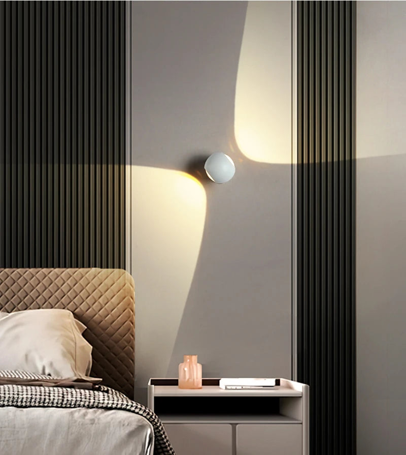 Modern bedroom with a bed, nightstand, and wall lights.