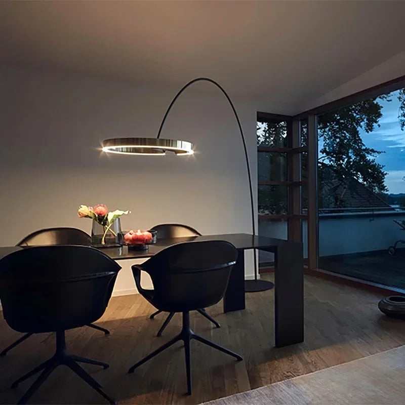 Modern dining room with a black table and chairs, featuring a floor lamp.