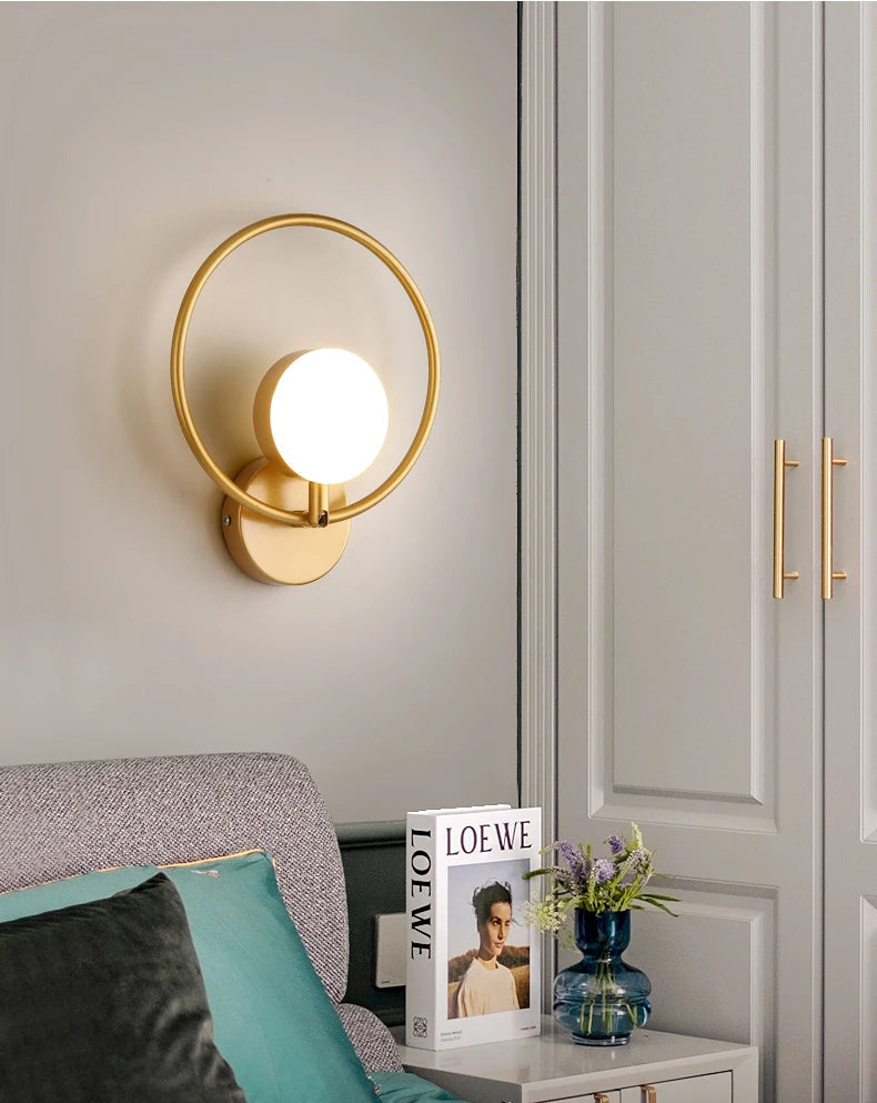 Gold wall sconce on a wall with a sofa and decorative items in the foreground