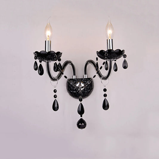 Black wall sconce with two flame-shaped LED bulbs and cascading black crystals, mounted on a white wall.