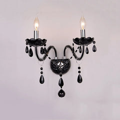 Black wall sconce with two flame-shaped LED bulbs and cascading black crystals, mounted on a white wall.