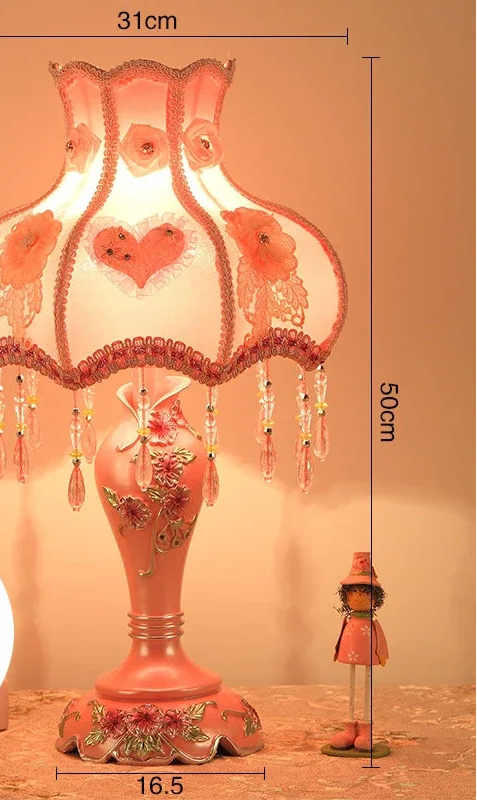 Decorative table lamp with floral design and remote control on a wooden surface.