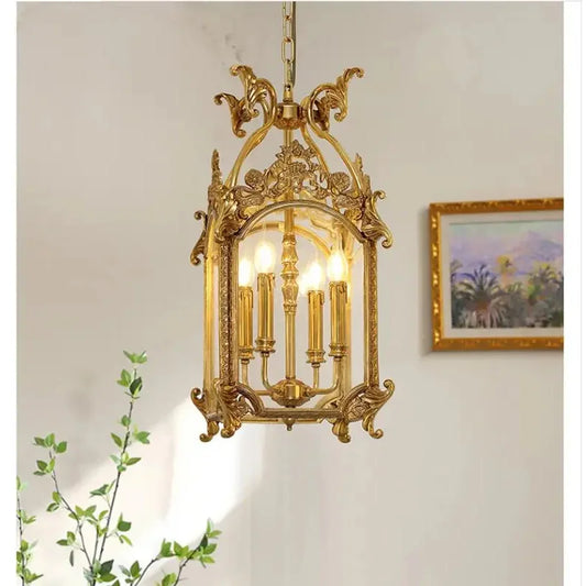 A gold candelabra-style pendant light with a decorative cage frame, hanging in a well-lit room with a painting on the wall.