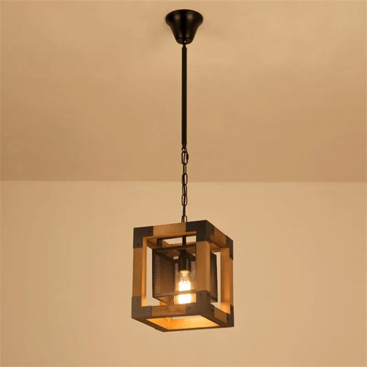 Square industrial pendant light with wood frame and dark metal cage, featuring one exposed bulb suspended by a chain from a ceiling canopy.