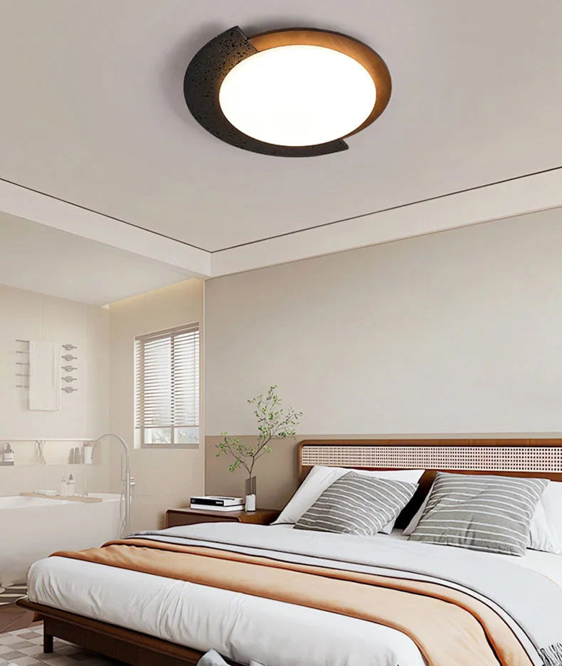 Ceiling light fixture in a bedroom setting with a bed and window in the background.