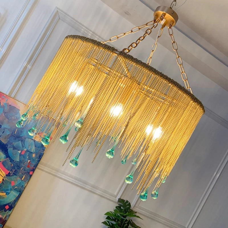 Close-up angled view of a gold chain tassel teardrop pendant light with blue-green glass accents