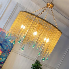 Close-up angled view of a gold chain tassel teardrop pendant light with blue-green glass accents
