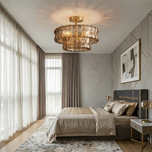 Gold wavy glass chandelier installed in a modern bedroom, illuminating the space above the bed