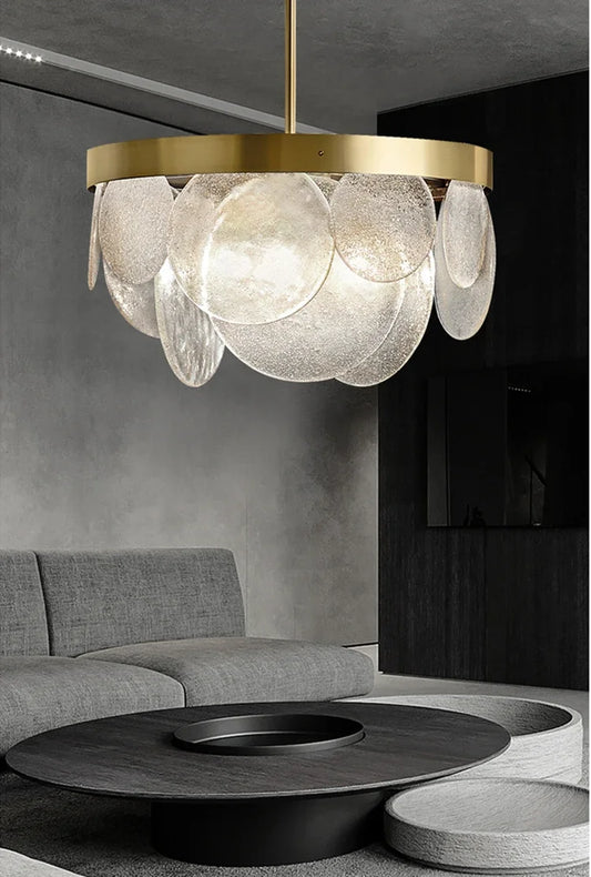 A modern gold chandelier with cascading clear glass discs hanging above a coffee table in a living room.