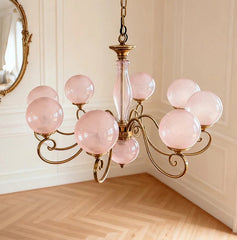A multi-light gold pendant fixture with pink glass shades, showcasing its curved arms and central stem.
