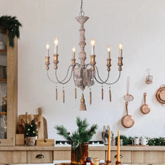 A distressed wood tassel chandelier as the central light fixture in a kitchen or dining area with wooden cabinetry and holiday decorations.