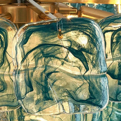 Close-up view of textured amber glass panels from the chandelier, with visible light reflections and swirling colors.