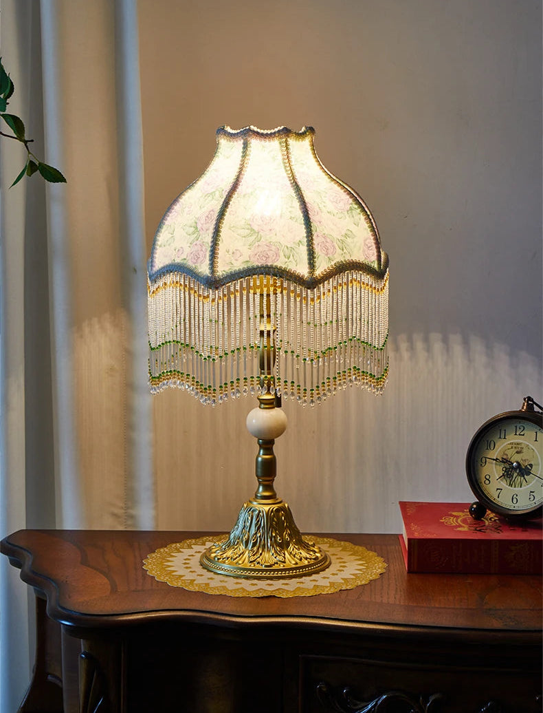 Decorative table lamp with a beaded shade on a wooden surface.