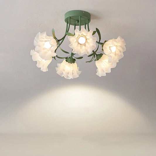 Green semi-flush mount ceiling light with five white frosted glass flower bud shades and green metal leaf accents, casting a warm glow on a white ceiling.