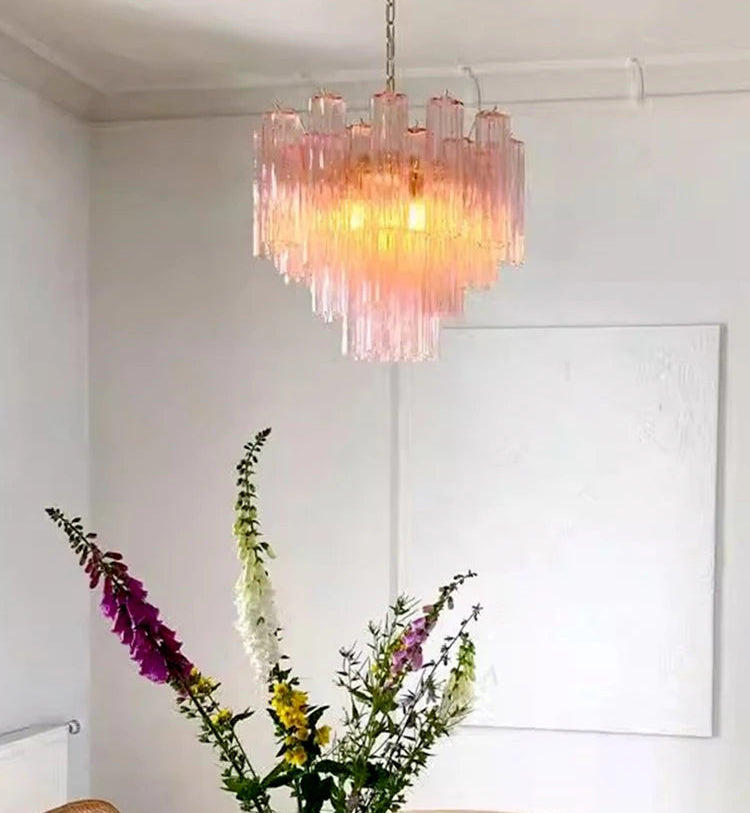 Pink chandelier hanging in a room with a vase of flowers on a table.