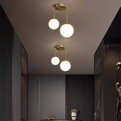 A modern hallway illuminated by two gold arch globe semi-flush ceiling lights.