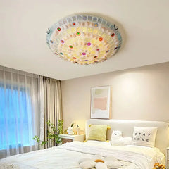 A bedroom scene with a mosaic flush mount ceiling light and sheer curtains.