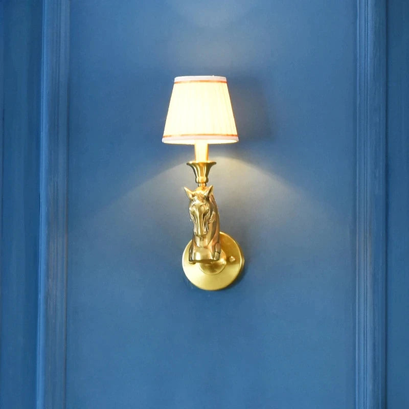 Gold wall sconce with a horse head design on a blue wall