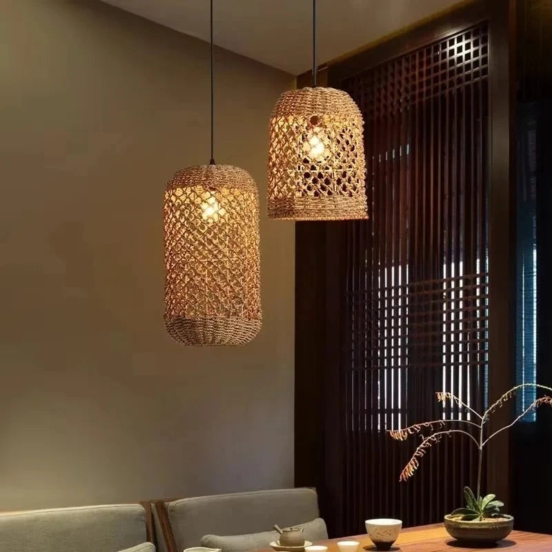 Two cylindrical woven bamboo pendant lights hanging in a dining area with a dark wood partition in the background.