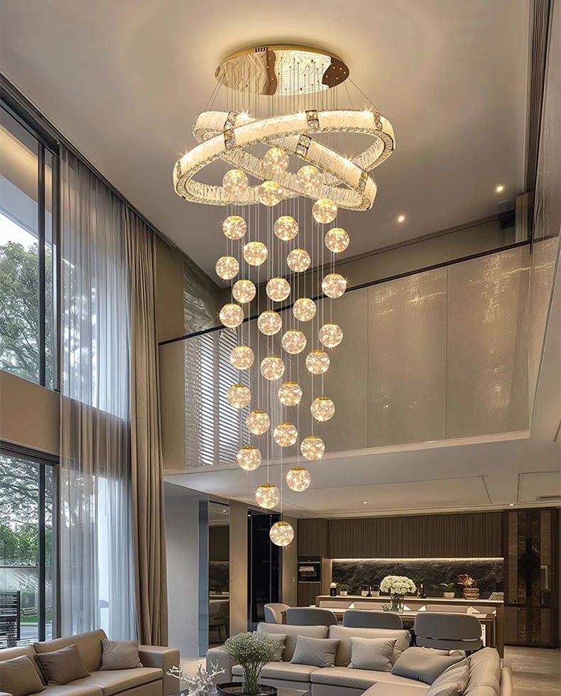 Modern chandelier hanging in a living room with large windows and furniture.