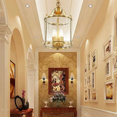 Gold lantern pendant light in a hallway with ornate wallpaper and a collection of framed pictures on the wall.