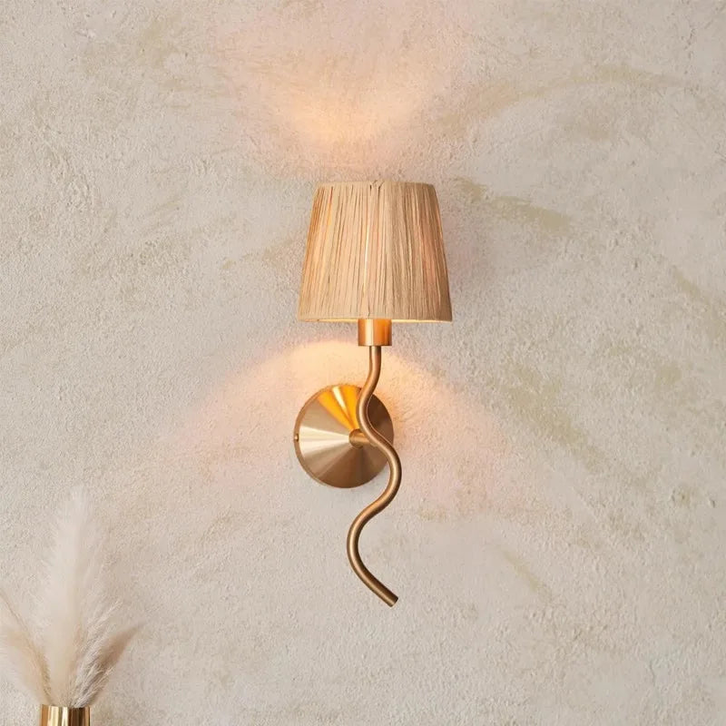Decorative wall lamp with a gold spiral design on a textured beige wall.