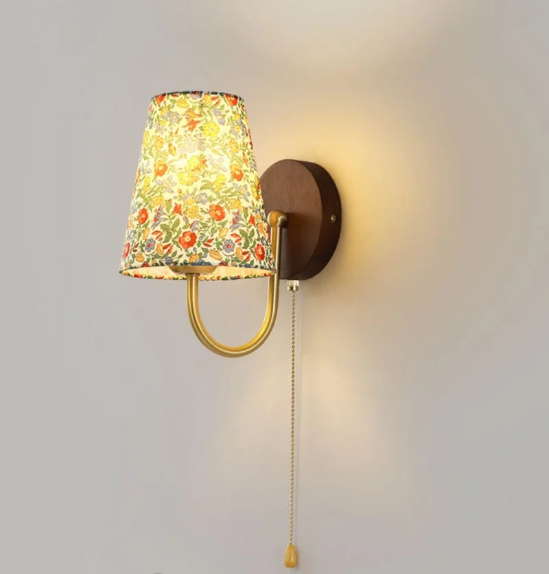 Wall-mounted lamp with floral-patterned shade on a plain background