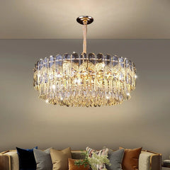 A luxurious tiered gold crystal chandelier with cascading teardrop crystals, illuminating a modern living room.
