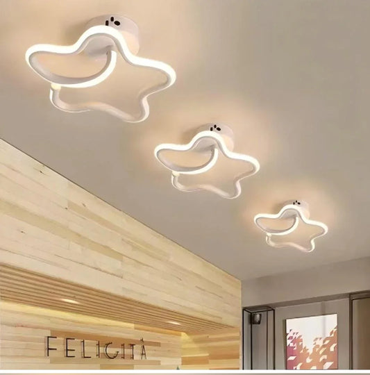 Three white star-shaped semi-flush mount ceiling lights mounted on a light wood paneled ceiling