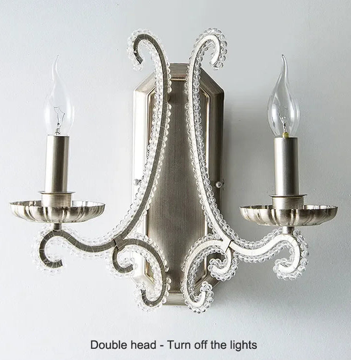 Decorative wall sconce with two candle-style lights on a plain background