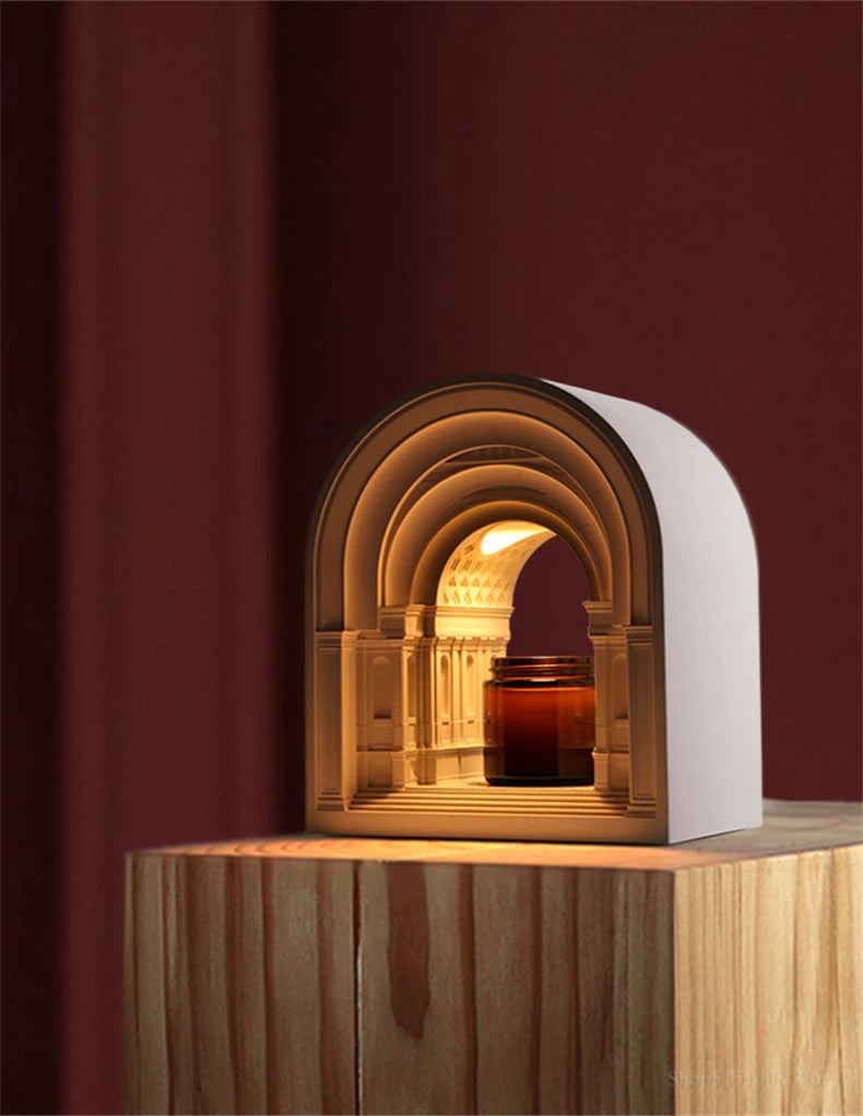 Decorative arch with a candle inside on a wooden surface against a dark red background